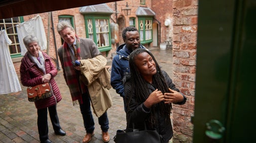 People looking round a brick courtyard with washing hanging out